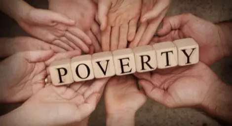 Hands holding the word poverty on cubes.